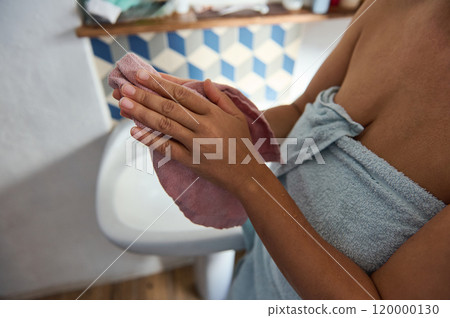 Woman drying hands with towel in cozy bathroom setting 120000130
