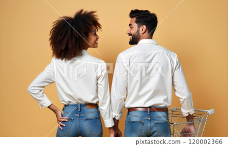 A couple smiles playfully while facing each other against a pastel backdrop, highlighting their casual outfits 120002366