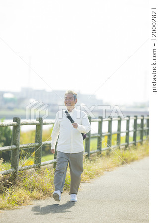 一位老人興高采烈地沿著堤岸行走 120002821
