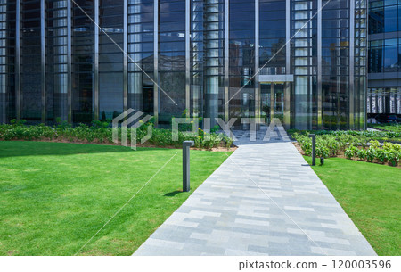 Stone path leading to modern office building entrance surrounded by green grass 120003596
