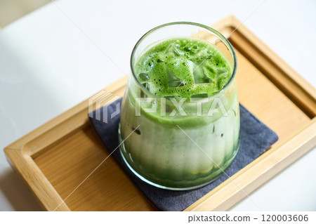 Iced matcha green tea latte sitting on wooden tray 120003606