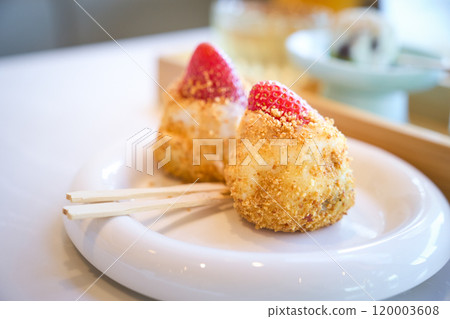 Two pieces of daifuku mochi topped with strawberries are sitting on a white plate Two pieces of daifuku mochi topped with strawberries are sitting on a white plate 120003608