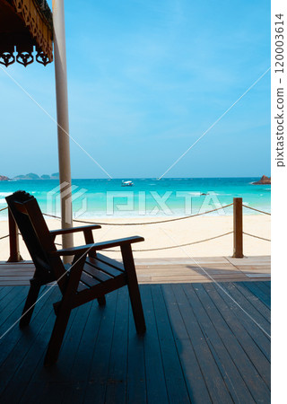 Wooden chair standing on a terrace facing the turquoise sea Wooden chair standing on a terrace facing the turquoise sea 120003614