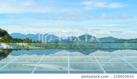 Empty glass floor platform reflecting majestic mountains and sky 120003654