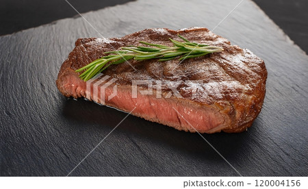 Medium rare juicy steak, parchment paper and rosemary on a slate plate 120004156
