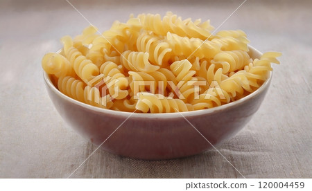 A bowl of raw rotini pasta, a type of pasta that is shaped like a spiral or a bottle of wine A bowl of raw rotini pasta, a type of pasta that is shaped like a spiral or a bottle of wine 120004459