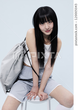Korean Woman in Her 20s Poses Sitting on Chair in Block Core fashion 120005043