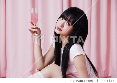 A Korean woman in her 20s holding a champagne glass with a pink drink on a pink background A Korean woman in her 20s holding a champagne glass with a pink drink on a pink background 120005142