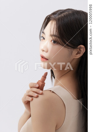 a woman holding a lipstick in the sun 120005998