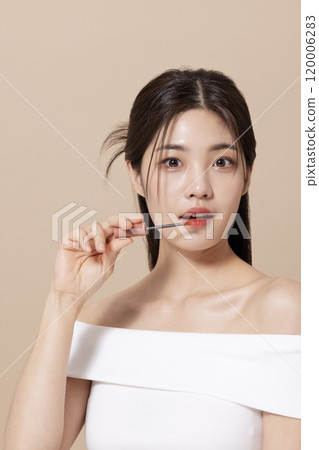 a woman in her 20s holding cosmetics in front of a table decorated with flowers a woman in her 20s holding cosmetics in front of a table decorated with flowers 120006283