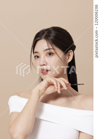 a woman in her 20s holding cosmetics in front of a table decorated with flowers a woman in her 20s holding cosmetics in front of a table decorated with flowers 120006286