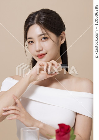a woman in her 20s holding cosmetics in front of a table decorated with flowers 120006298