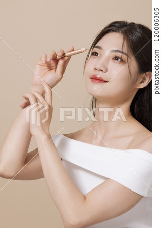 a woman in her 20s holding cosmetics in front of a table decorated with flowers a woman in her 20s holding cosmetics in front of a table decorated with flowers 120006305