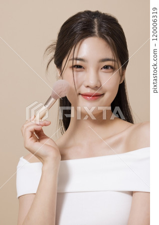 a woman in her 20s holding cosmetics in front of a table decorated with flowers 120006319