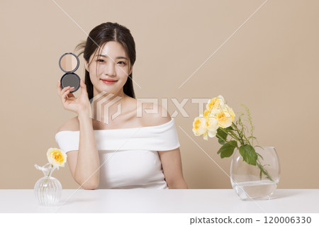 a woman in her 20s holding cosmetics in front of a table decorated with flowers a woman in her 20s holding cosmetics in front of a table decorated with flowers 120006330