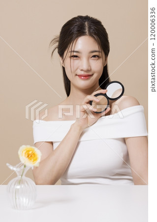 a woman in her 20s holding cosmetics in front of a table decorated with flowers a woman in her 20s holding cosmetics in front of a table decorated with flowers 120006336