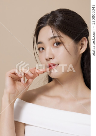 a woman in her 20s holding cosmetics in front of a table decorated with flowers 120006342