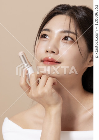 a woman in her 20s holding cosmetics in front of a table decorated with flowers a woman in her 20s holding cosmetics in front of a table decorated with flowers 120006352