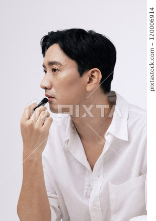 A pose of a middleaged man applying lip balm to his lips A pose of a middleaged man applying lip balm to his lips 120006914