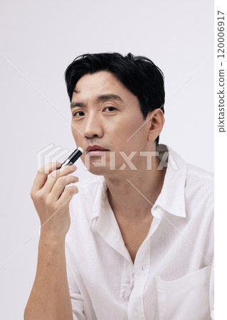 A pose of a middleaged man applying lip balm to his lips A pose of a middleaged man applying lip balm to his lips 120006917