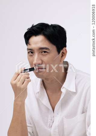 A pose of a middleaged man applying lip balm to his lips A pose of a middleaged man applying lip balm to his lips 120006918