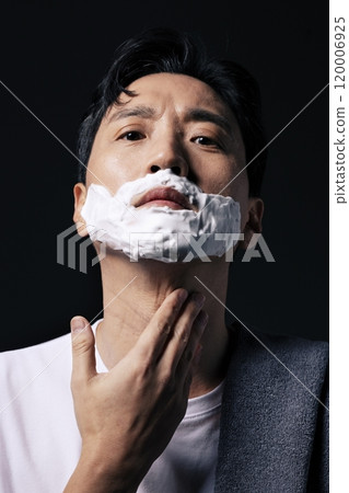 Middleaged man applying shaving cream to his face with one hand Middleaged man applying shaving cream to his face with one hand 120006925