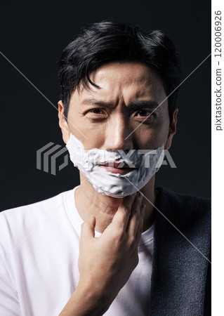 Middleaged man applying shaving cream to his face with one hand Middleaged man applying shaving cream to his face with one hand 120006926