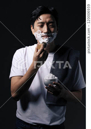 Middleaged man applying foam to his chin with a shaving brush 120006939