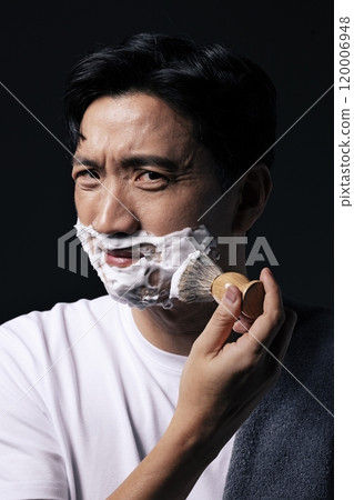 Middleaged man applying foam to his face with a shaving brush Middleaged man applying foam to his face with a shaving brush 120006948