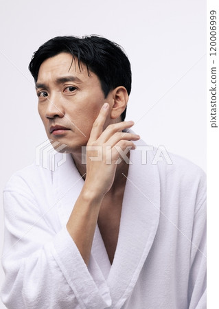 A middleaged man with his hand brushing his chin 120006999
