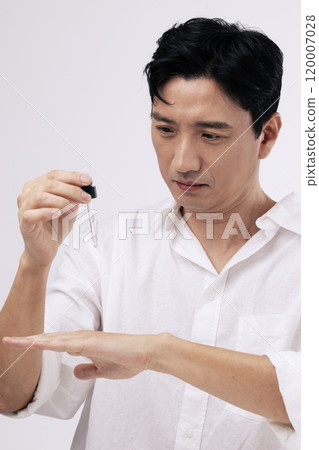 A middleaged man dropping an ampoule on the back of his hand 120007028
