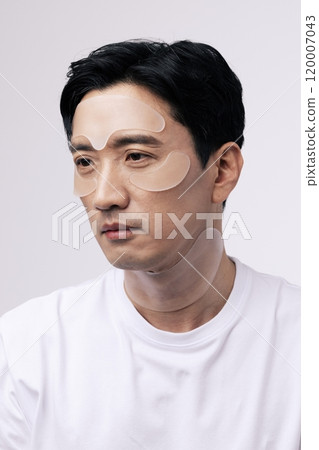 Middleaged man with cosmetic patches around his eyes 120007043