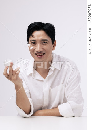 A middleaged man holding a can of cream with a bright expression 120007078