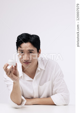 A middleaged man smiling and holding a can of cream 120007079