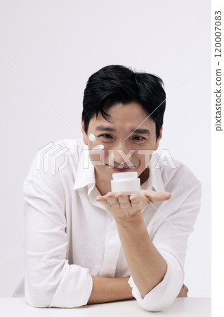 A middleaged man staring at the cream container in his palm with a smiling expression 120007083