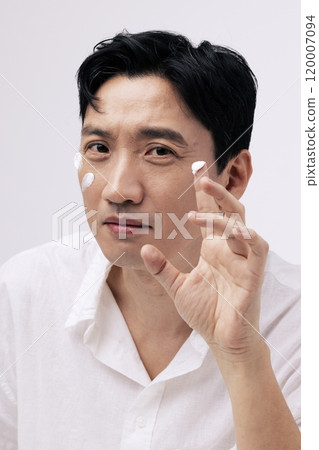 Middleaged man applying cream with his fingers and looking straight ahead 120007094