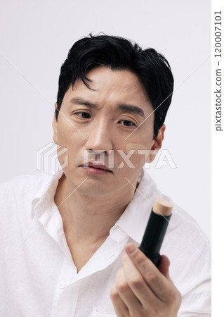 Middleaged man looking at stick foundation Middleaged man looking at stick foundation 120007101