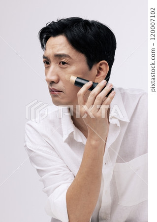 Middleaged man applying foundation to his face Middleaged man applying foundation to his face 120007102