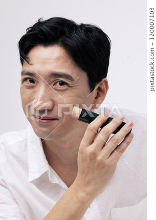 Middleaged man smiling and applying foundation to his face Middleaged man smiling and applying foundation to his face 120007103