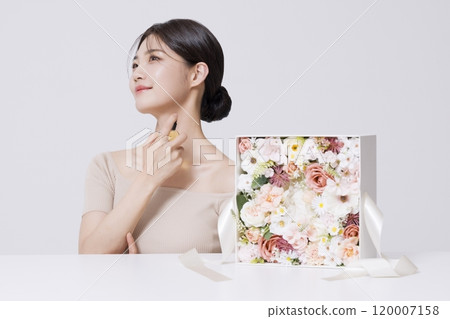 a woman holding up cosmetics to wrap them up 120007158