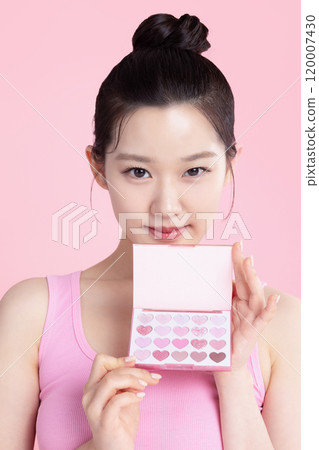 A teenage woman posing with an eyeshadow palette 120007430