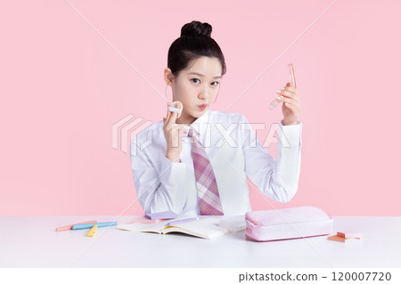 A teenage woman wearing a school uniform and holding cosmetics in a cute pose A teenage woman wearing a school uniform and holding cosmetics in a cute pose 120007720