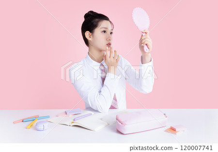 A teenage woman wearing a school uniform and holding cosmetics in a cute pose A teenage woman wearing a school uniform and holding cosmetics in a cute pose 120007741