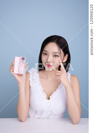 A woman in her 20s posing with a cool-toned color shadow palette 120008120