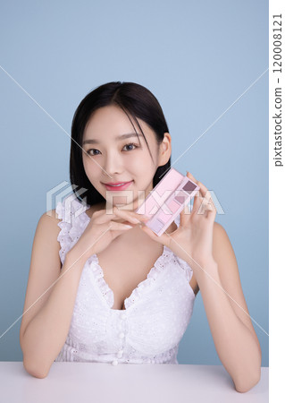 A woman in her 20s posing with a cool-toned color shadow palette A woman in her 20s posing with a cool-toned color shadow palette 120008121