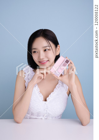 A woman in her 20s posing with a cool-toned color shadow palette A woman in her 20s posing with a cool-toned color shadow palette 120008122