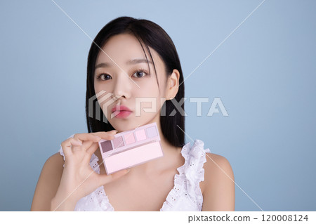 A woman in her 20s posing with a cool-toned color shadow palette 120008124