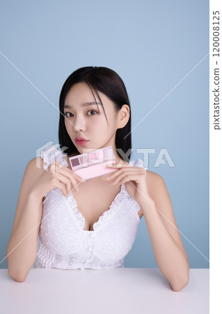 A woman in her 20s posing with a cool-toned color shadow palette 120008125