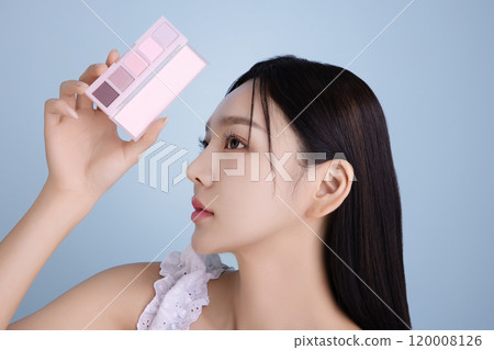 A woman in her 20s posing with a cool-toned color shadow palette 120008126