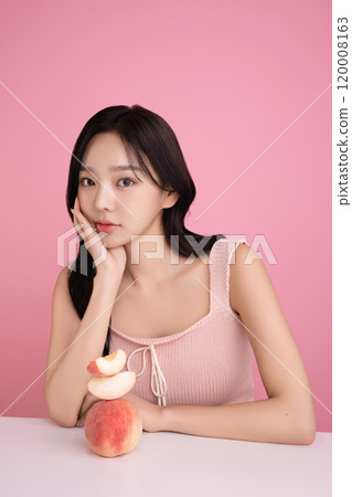 A woman in her 20s posing with a peach on the table A woman in her 20s posing with a peach on the table 120008163